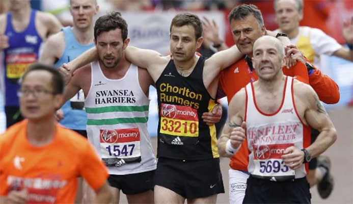 Matthew Rees helps the exhausted runner across the line CREDIT: LONDON MARATHON 